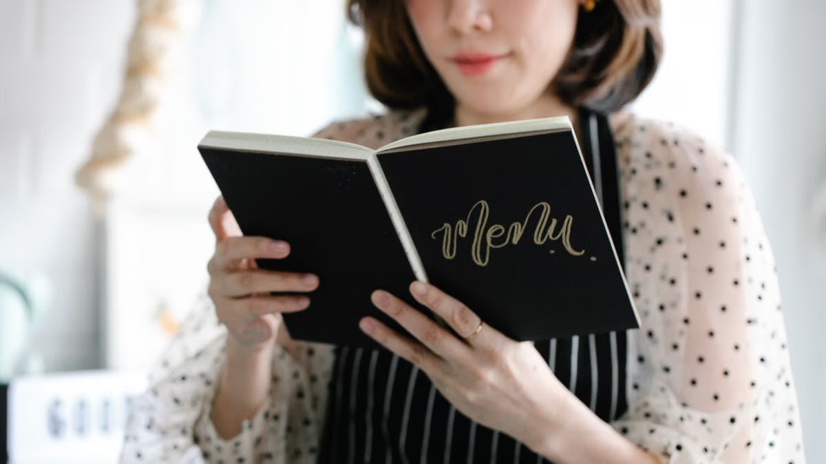 Close-up of a woman holding and reading a menu indoors.